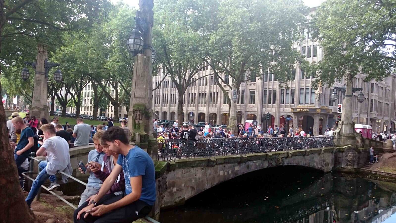 Leute sitzen mit Handy auf Brücke